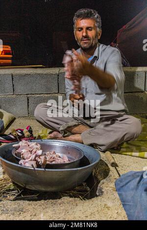 ZAGROS, IRAN - JULY 7, 2019: Nomad preparing chicken skewers in Zagros mountains, Iran Stock Photo
