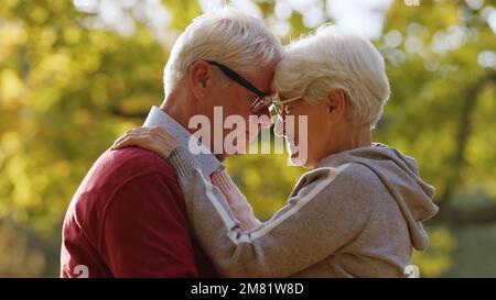 Senior grey-haired man and woman in love hugging and touching foreheads. High quality photo Stock Photo