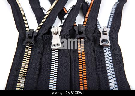 Jacket Winter Coat Black Tape Heavy Duty Zippers Large Molded Plastic Zippers. Close-up of zipper slider on a white surface. Sewing production, materi Stock Photo