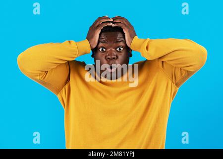 Portrait Of Shocked Black Young Man Opening Mouth And Touching Head Stock Photo