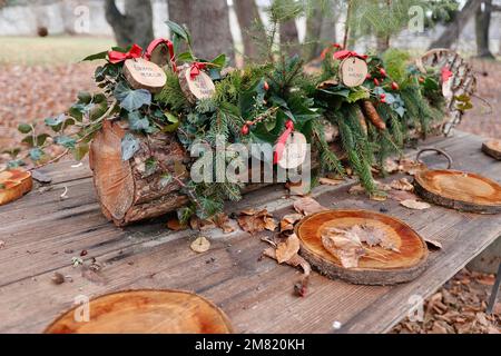 An outdoor table is decorated with a Christmas wreath and place settings made of wood. Children have written messages of hope on the decorations Stock Photo
