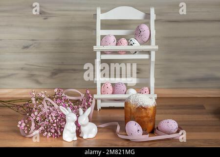 Two Easter Bunnies. Easter background with colored Easter eggs and blooming flowers. Kulich. Easter composition. Stock Photo