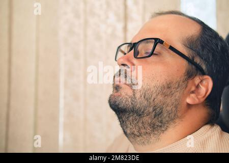 A European man in glasses and headphones sleeping at workplace Stock Photo