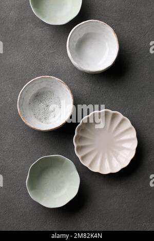 various empty bowls on dark grey background, top view Stock Photo