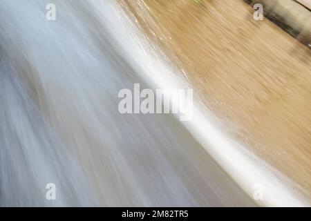 Dynamic texture of fast moving water, in yellowish soft tones. Concepts of nature and motion. Stock Photo