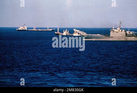 The tank landing ship USS SUMTER (LST 1181) is utilized to assist in the rescue of crewmen from the sinking Panamanian ship 'SKY ONE' visible off the Sumter's starboard bow. Another merchant ship is also visible in the background. Country: Mediterranean Sea (MED) Stock Photo