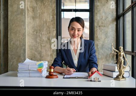 Professional and gorgeous millennial Asian female lawyer or business legal consultant sits at her desk in the office. Stock Photo