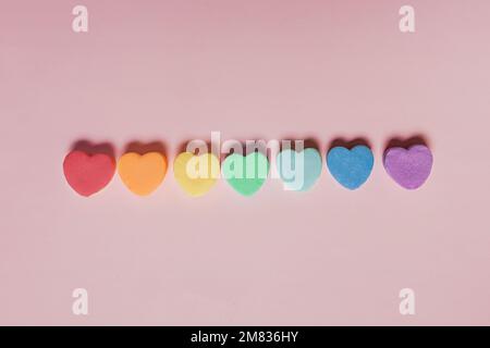 Rainbow colored heart shaped candies on pink background, Valentine's day concept Stock Photo