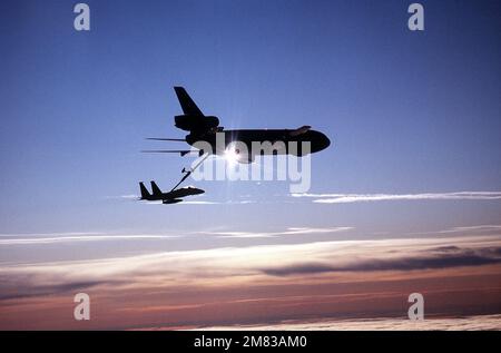 An air-to-air right side silhouetted view of an F-15 Eagle aircraft being refueled from a KC-10A Extender aircraft during Exercise Brim Frost '85. Subject Operation/Series: BRIM FROST '85 Country: United States Of America (USA) Stock Photo