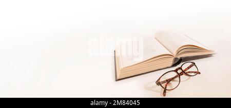 Long-sighted glasses and a big book. laying on a white background. Elderly eye health problems. Stock Photo