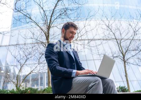 A handsome young businessman working on computer outside the office in a business park Stock Photo