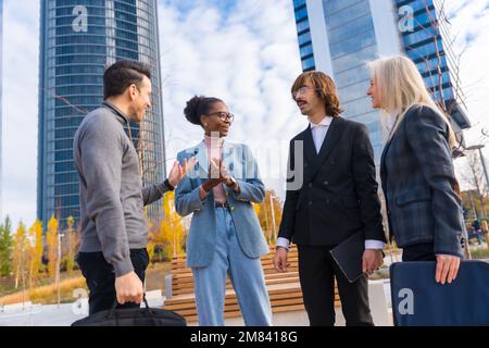 A group of multi-ethnic business people outside the glass office building talking about work Stock Photo