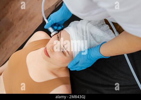 Therapist beautician makes a rejuvenating facial massage for the model Stock Photo