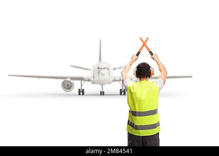 Rear view shot of a marshaller signalling with crossed wands in front of an aircraft isolated on white background Stock Photo
