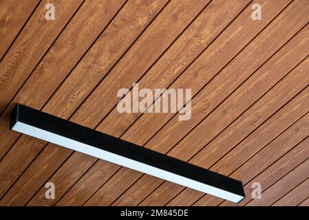 PVC ceiling panel covered with wood-like vinyl with modern lighting installed on it Stock Photo