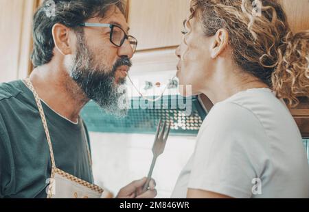 One man and woman eating spaghetti together in romantic activity. Happy husband and wife in love cooking and enjoying love and life. Funny real life i Stock Photo