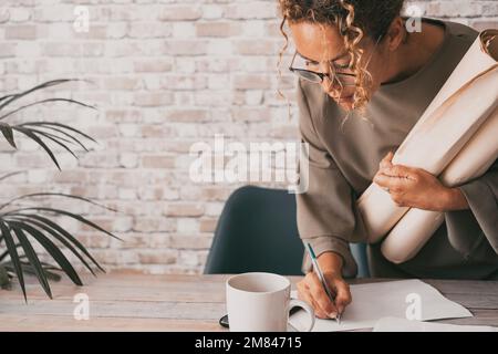 Businesswoman at work writing notes on sheet paper on the desk holding documents. Entrepreneur and modern female working concept lifestyle. Female peo Stock Photo