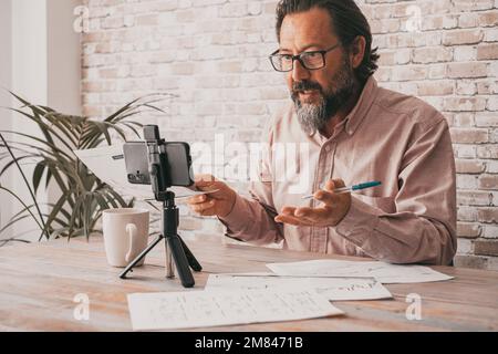 One worker man recording business content using mobile phone and tripod to share online on social media channel. New alternative work job business occ Stock Photo