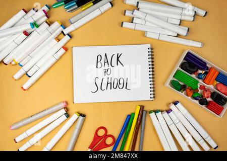 Many different office supplies. School markers, pens and plasticine. Inscription on notebook back to school Stock Photo