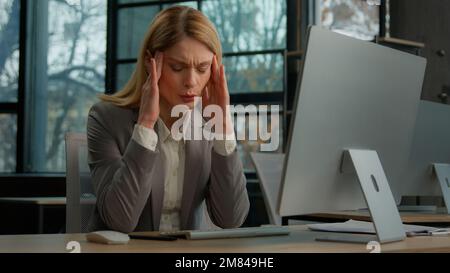 Frustrated sick ill sad Caucasian middle-aged adult woman mature business female lady businesswoman worker employer executive in office with computer Stock Photo