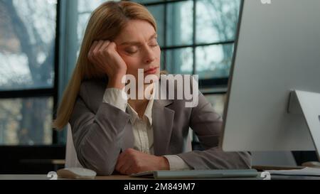 Tired sleeping lazy napping businesswoman boring with work in office with computer overworked exhausted sick ill woman worker need some rest at Stock Photo