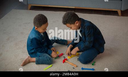 Ethnic African American multiracial multiethnic boys kids schoolboys pupils sons indoors at home children brothers cousins friends on floor carpet Stock Photo