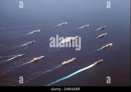 Aerial starboard quarter view of Battle Group Alfa underway. The ships are: (clockwise, center front) USS REEVES (CG-24) , USS SAN JOSE (AFS-7), USNS MISPILLION (T-AO-105), USS OLDENDORF (DD-972), USS KANSAS CITY (AOR-3), USNS KILAUEA (T-AE-26), USS ENGLAND (CG-22), USS TOWERS (DDG-9), USS KIRK (FF-1087), USS KNOX (FF-1052), USS COCHRANE (DDG-21), and USS MIDWAY (CV-41) (center). Base: Makassar Strait Country: Indonesia (IDN) Stock Photo