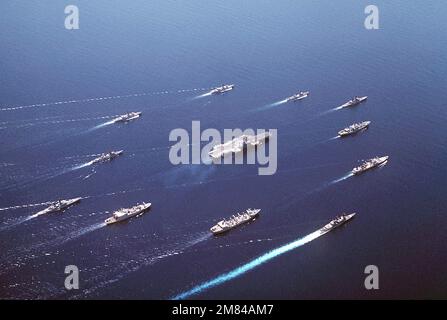 An aerial starboard quarter view of Battle Group Alfa underway. The ships are: (clockwise from center front) the USS REEVES (CG-24) , USS SAN JOSE (AFS-7), USNS MISPILLION (T-AO-105), USS OLDENDORF (DD-972), USS KANSAS CITY (AOR-3), USNS KILAUEA (T-AE-26), USS ENGLAND (CG-22), USS TOWERS (DDG-9), USS KIRK (FF-1087), USS KNOX (FF-1052), USS COCHRANE (DDG-21), and USS MIDWAY (CV-41) (center). Base: Makassar Strait Country: Indonesia (IDN) Stock Photo