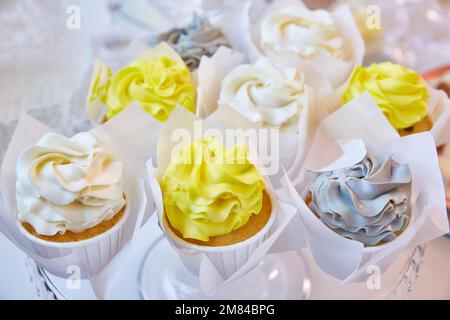 Delicious multicolored cupcakes on a white table. Stock Photo