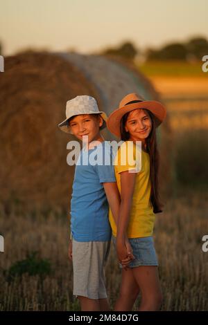 boy and a girl stand with their backs to each other in bright summer clothes Stock Photo