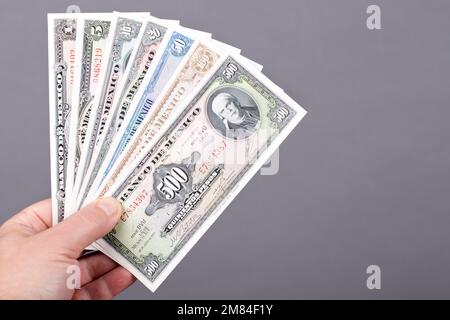 Old Mexican money - Pesos in the hand on a gray background Stock Photo