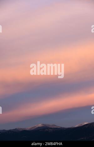 Stunning sunset with beautiful shades of orange, pink, purple and blue colors with the silhouette of a mountain range. Stock Photo