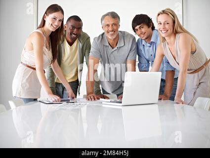 Dynamic business pros. Five colleagues using a laptop in the boardroom. Stock Photo