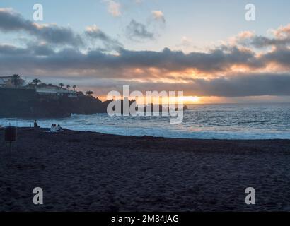 Santiago del Teide, Tenerife, Canary Islands, Spain, december 21, 2021: Sunset view of black sand beach Playa de la Arena with dramatic orange clouds Stock Photo
