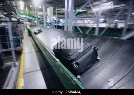 Traveling by airplane. Luggage on conveyor belt in blurred motion. Baggage sorting at airport. Stock Photo
