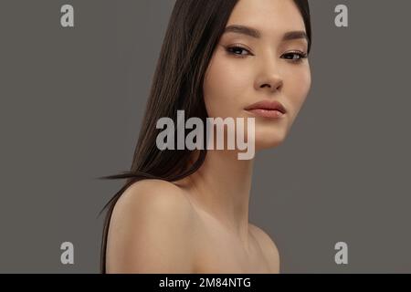 Young beautiful asian beauty model on a gray isolated background. Stock Photo