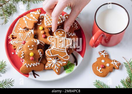 Gingerbread cookies in shape of ginger man placed on red plate. White background. Traditional Christmas dessert decorated. Playful and happy. Stock Photo