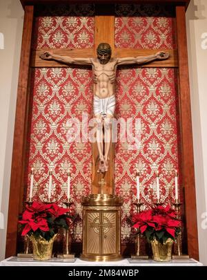 Jesus on the cross with tabernacle and poinsettias and candles for Christmas at St. Joseph's Catholic Church in Taylors Falls, Minnesota USA. Stock Photo