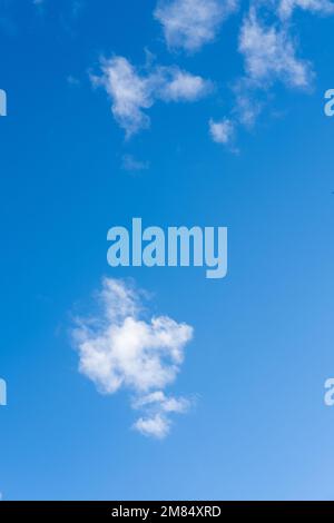 Blue sky with fluffy thin white clouds, vertical frame. Cloud background to overlay on your photos. Stock Photo