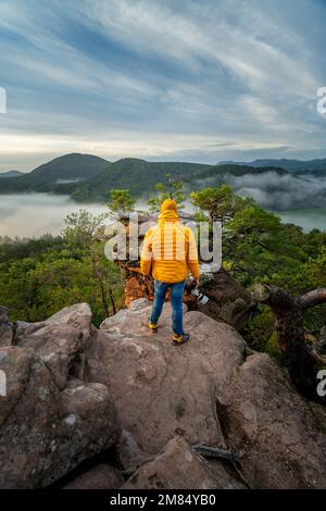 A man in a yellow jacket standing on top of a mountain Stock Photo
