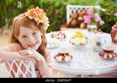 Tea-time with my Teddy. A little girl sitting outside having a tea party with her teddy bear. Stock Photo
