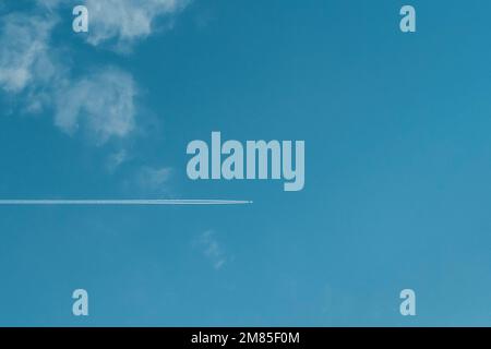 Jet trails of a plane among the clouds in the sky Stock Photo