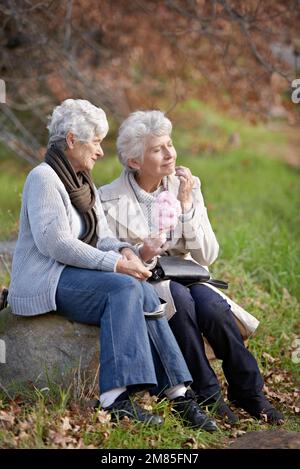 Best Friends for Life. Two senior women enjoying candy floss while sitting outside. Stock Photo