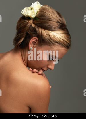 Grace and timeless elegance. Rearview studio shot of an attractive young woman with a flower in her hair. Stock Photo