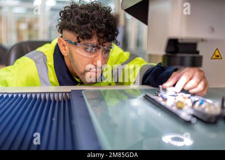 Engineer sitting in robot fabrication room use measuring microscope machine check electronic board Stock Photo