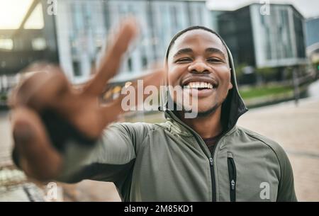 Fitness, selfie and portrait of a black man with peace sign in the city doing a cardio exercise. Happy, smile and real African guy taking picture Stock Photo