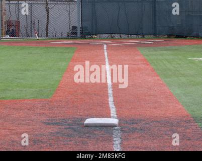 Looking down the white foul line from third base to the batter box of a turf baseball field Stock Photo