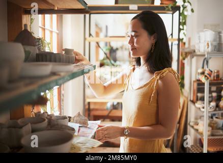 Pottery, startup and display with a woman entrepreneur working in a studio, selling products for retail. Small business, manager or sale with a female Stock Photo