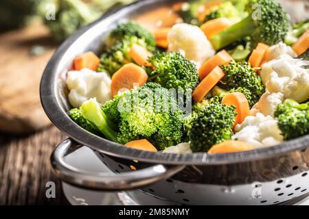 Steamed broccoli, carrots and cauliflower in a stainless steel steamer. Healthy vegetable concept. Stock Photo