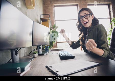 Profile portrait of excited crazy pc operator lady sitting chair raise fists finish done project loft interior indoors Stock Photo